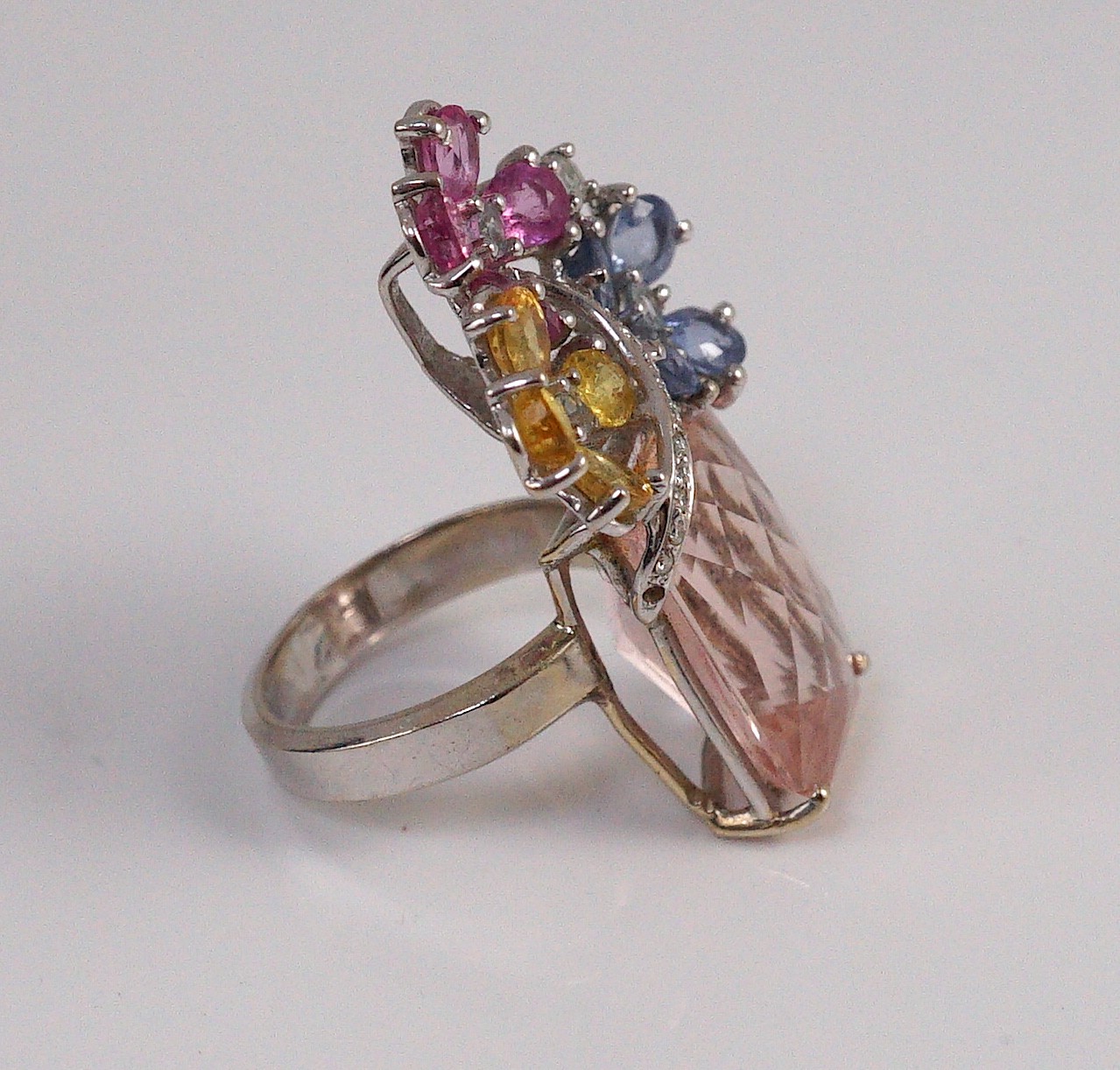 A large modern 14k white gold, morganite, four colour sapphire (including colourless) and diamond chip set triple flower head dress ring, in a raised setting
